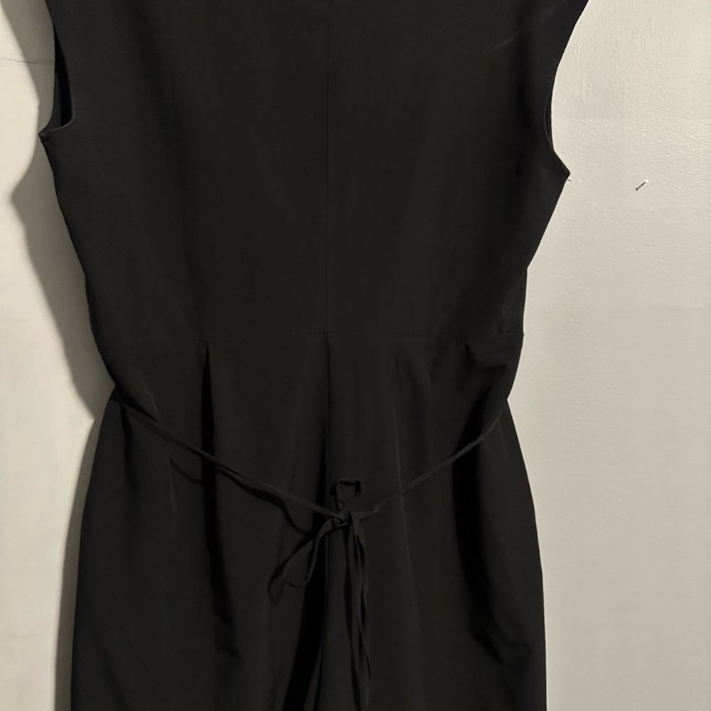 Black romper with functional tie, pockets and button at bust.